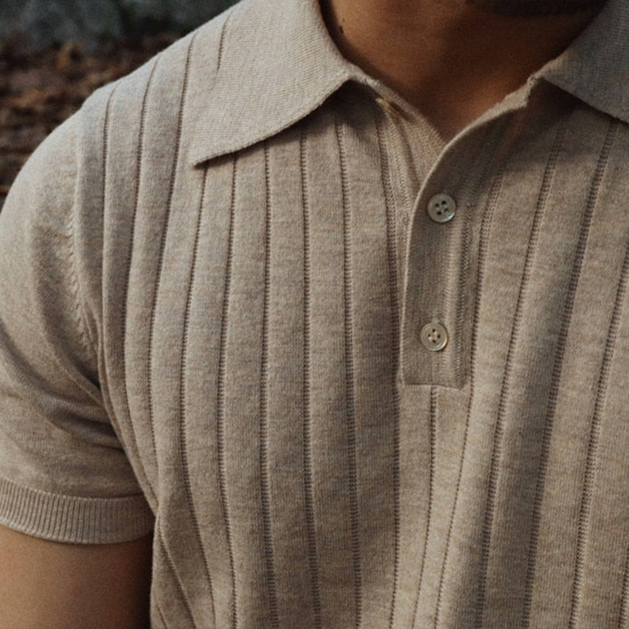 Beige strikket polo med knapper, ribbet mønster og kortærmet design. Stilfuld herremode, perfekt til casual og elegant look.
