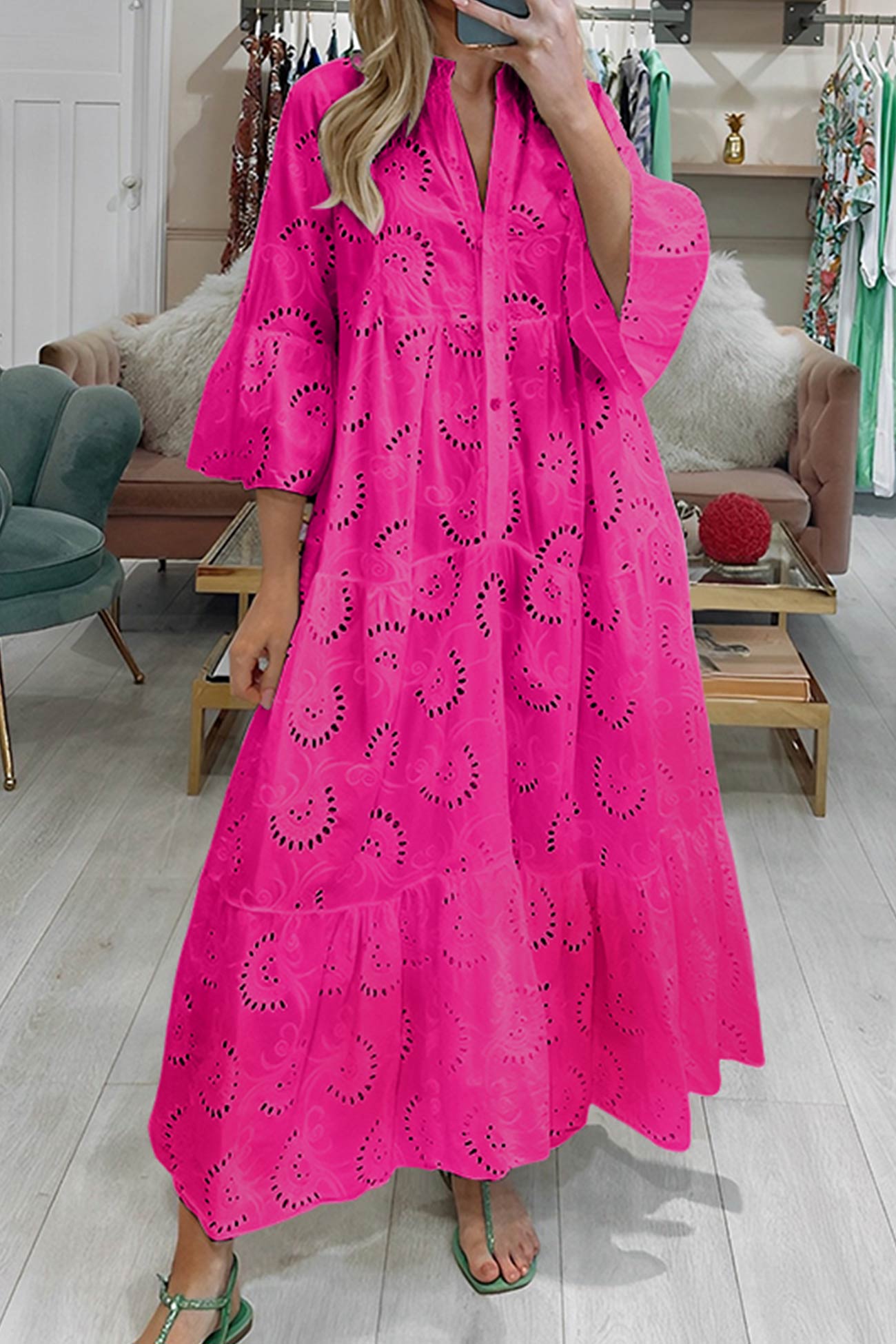 Kvinde iført lang, pink kjole med broderie anglaise mønster, står i moderne butik. Trendy sommermode, farverig kjole, stilfuldt design.