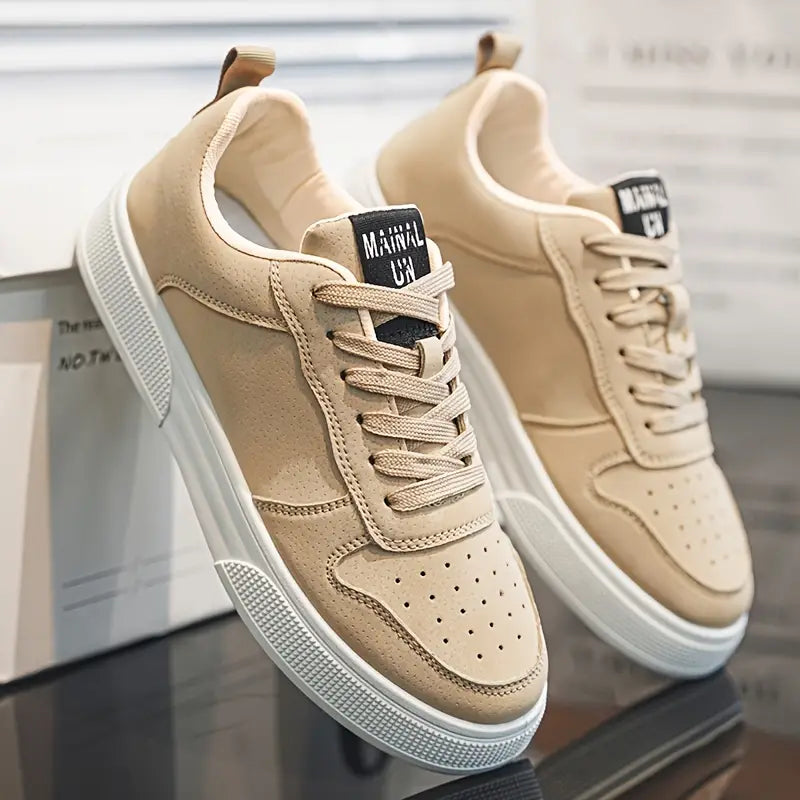 Beige sneakers med hvid sål, perforeret tå og snørebånd, placeret på en skotøjsæske. Moderne herresko, casual stil, komfortabelt design.