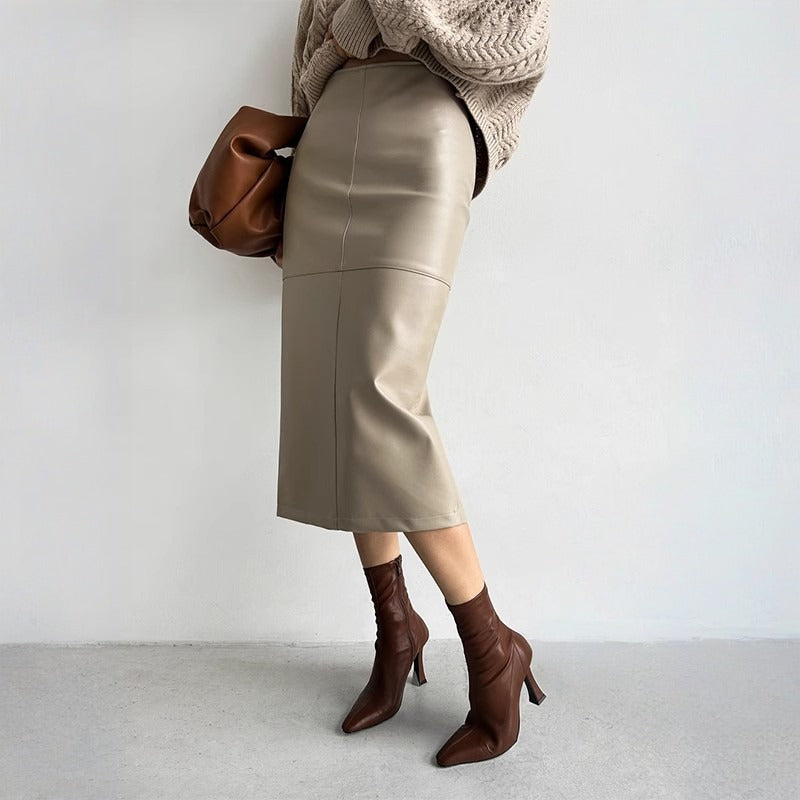 Kvinde iført beige lædernederdel, brun striktrøje og brune støvler. Mode, efterårstøj, stilfuldt outfit, moderne kvindemode.