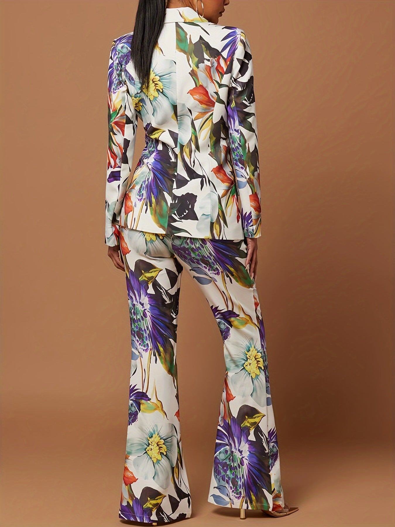 Kvinde iført farverig blomstret jakkesæt med lange ærmer og vide bukser, set bagfra. Trendy modetøj, elegant design, moderne stil.