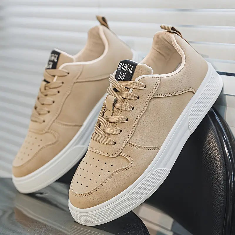 Beige sneakers med hvid sål, moderne design, snørebånd, perforeret tå, placeret på sort stol. Perfekte til casual og sporty stil.