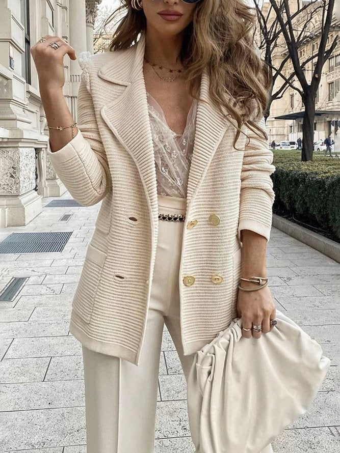 Kvinde iført elegant hvid blazer og blondebluse, holder en hvid taske. Mode, stilfuldt outfit, gadebillede, moderne kvindetøj, forårsmode.