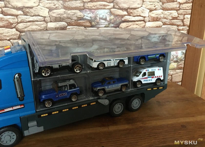 Blå legetøjslastbil med gennemsigtigt tag, der transporterer små politibiler og SUV'er. Perfekt til børn, der elsker legetøjsbiler og lastbiler.