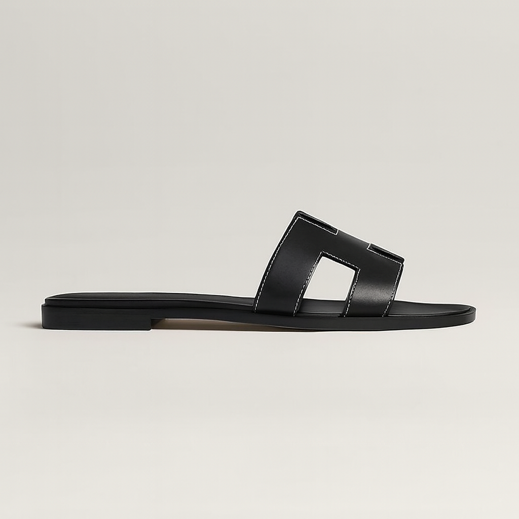 Sort læder sandal med flad sål og firkantet udskæring, minimalistisk design. Perfekt til sommermode og casual stil. Komfortabel og stilfuld.