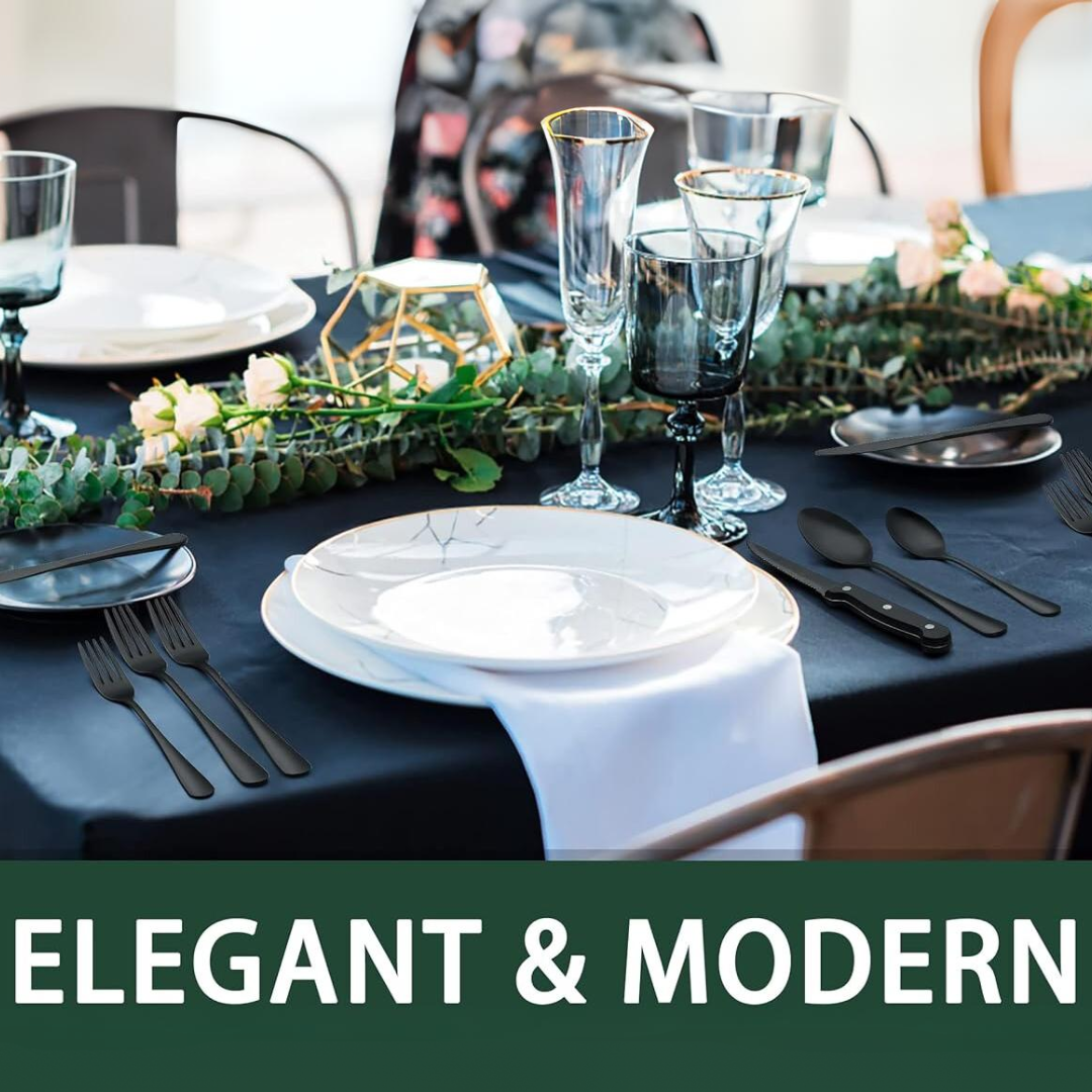 Elegant borddækning med sorte bestik, krystalglas og hvidt porcelæn på sort dug. Dekoreret med grønne blade og roser. Moderne middagsselskab.