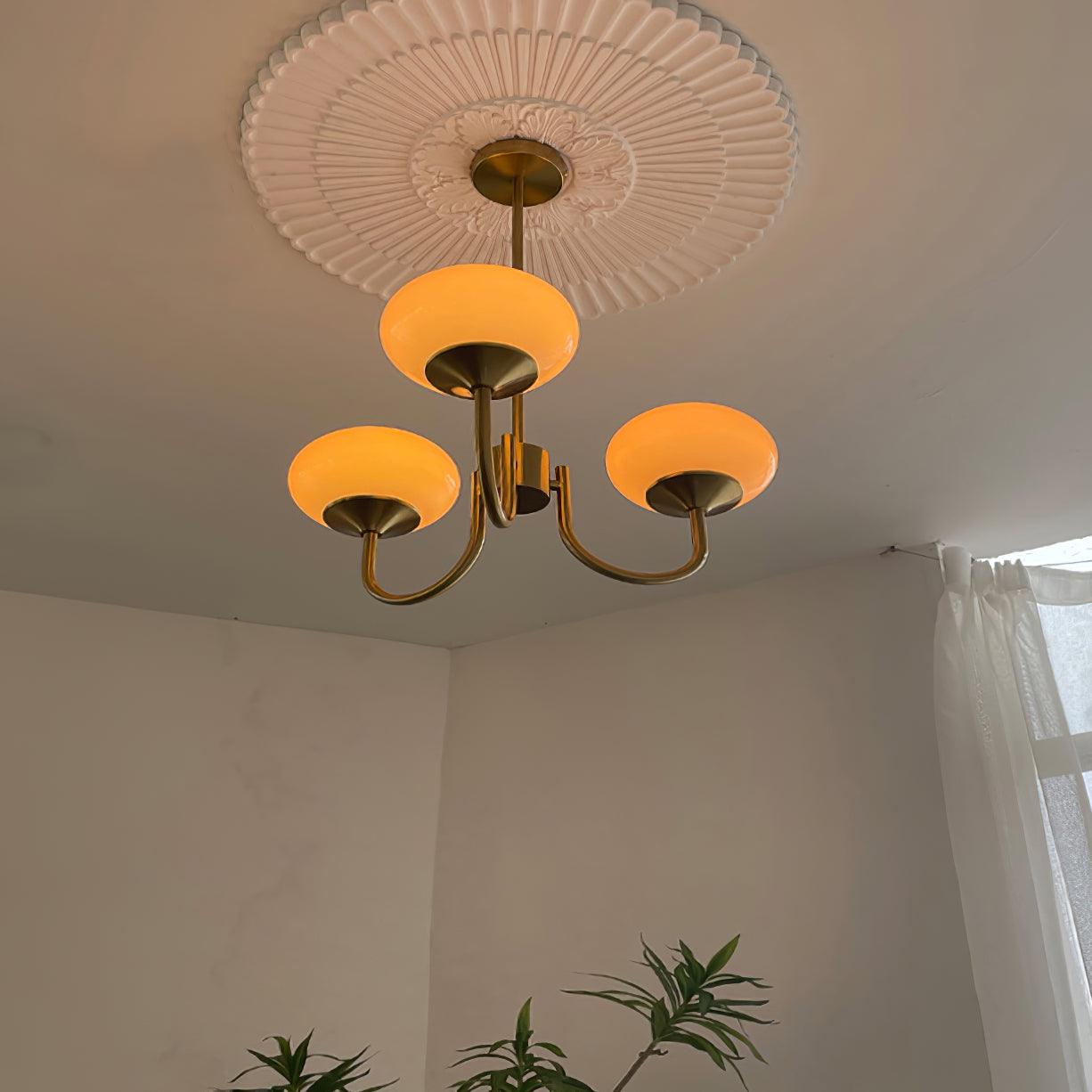 Moderne lysekrone med tre gyldne lamper, elegant loftsroset og minimalistisk design. Perfekt til stilfuld belysning i stue eller spisestue.