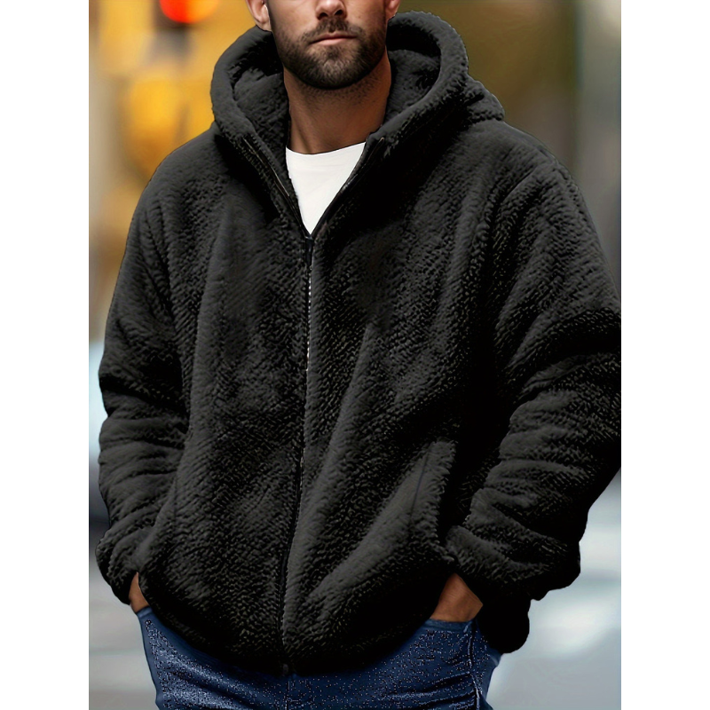 Mand iført sort teddyfleece jakke med hætte, står udendørs. Vintermode, varm jakke, casual stil. Perfekt til kolde dage.