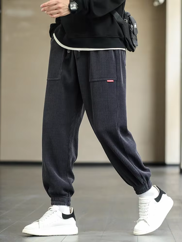 Mand iført sorte joggingbukser, hvide sneakers og sort sweatshirt. Moderne streetwear-stil, komfortabelt og afslappet look.