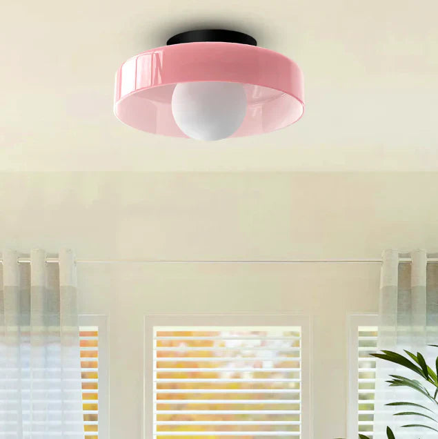 Lyserød loftlampe med rund skærm og hvid pære, moderne design, monteret i lyst rum med vinduer og gardiner. Perfekt til stilfuld belysning.