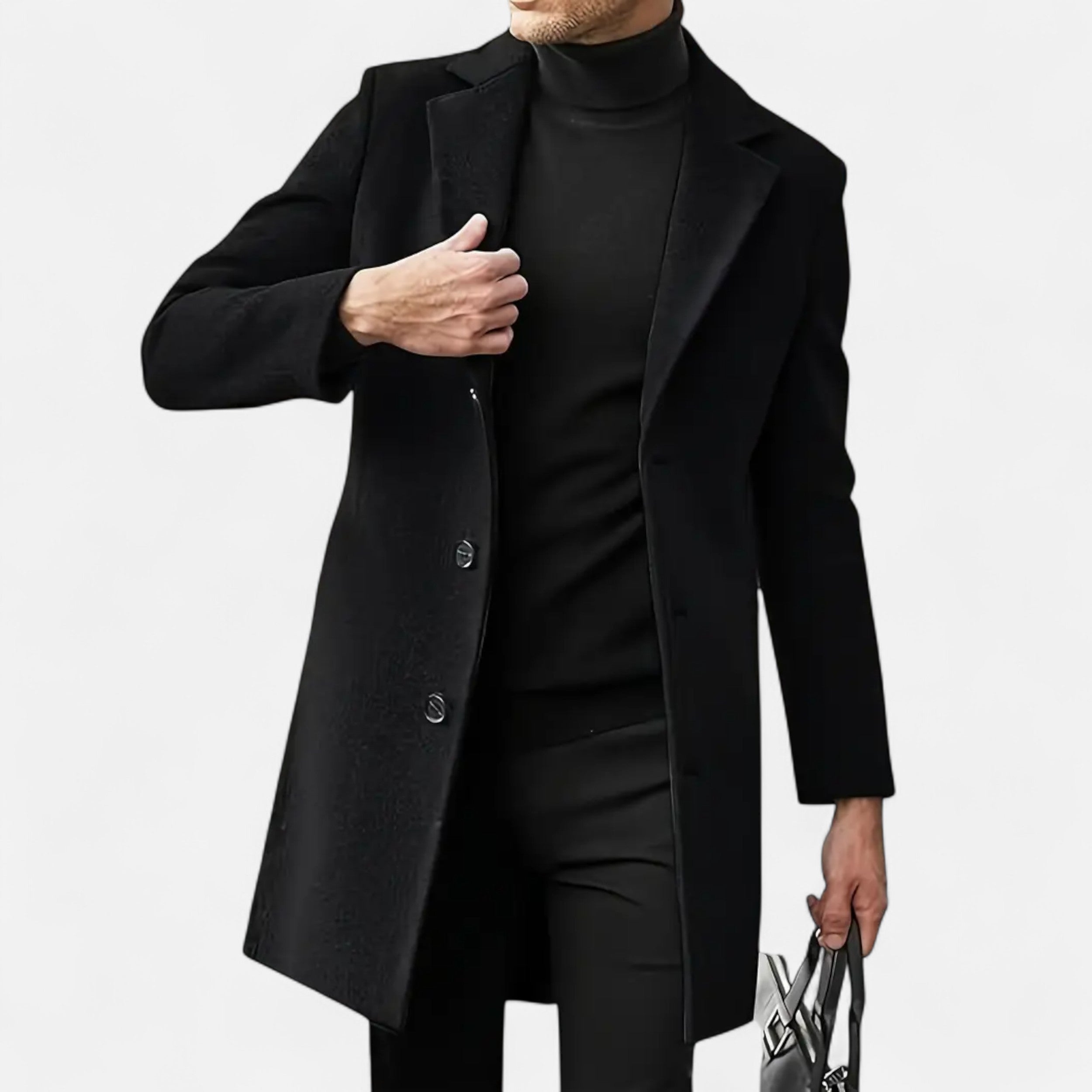 Mand iført sort frakke og sort turtleneck, holder en taske. Elegant herremode, vinterjakke, stilfuldt tøj til mænd.