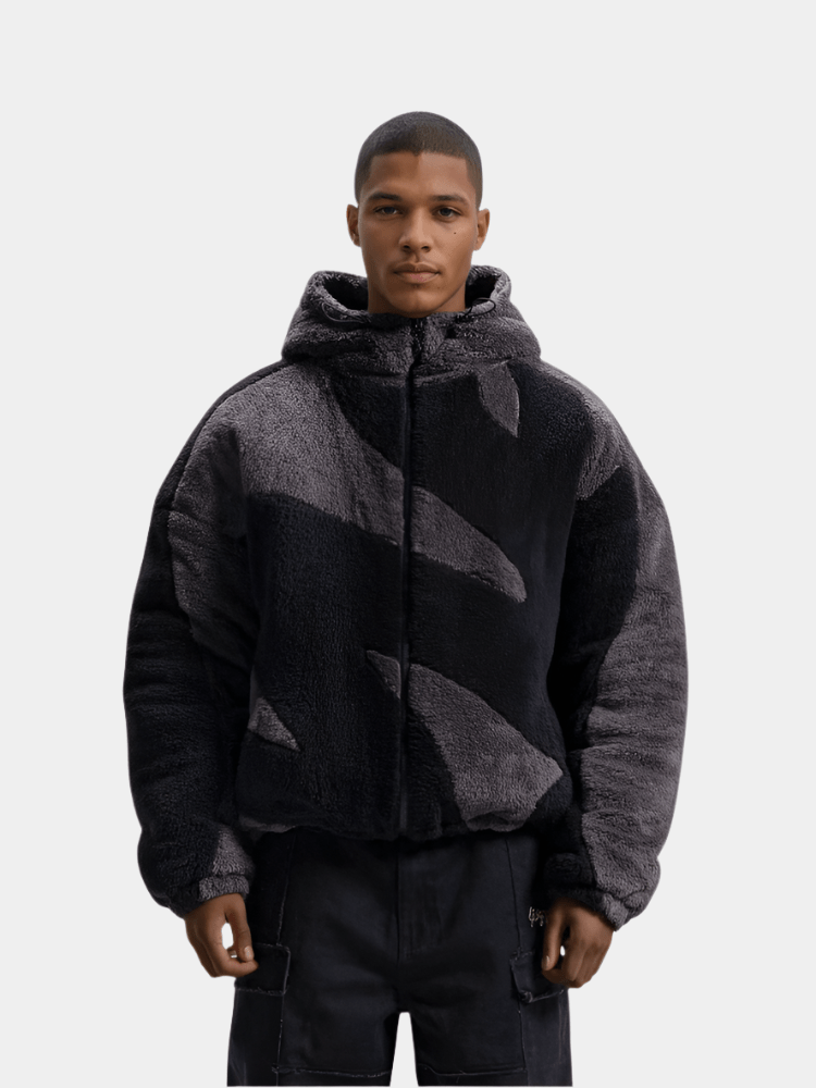 Ung mand iført sort og grå camouflage hættetrøje i plys, moderne streetwear stil, isoleret på hvid baggrund. Trendy herremode, vinterjakke.