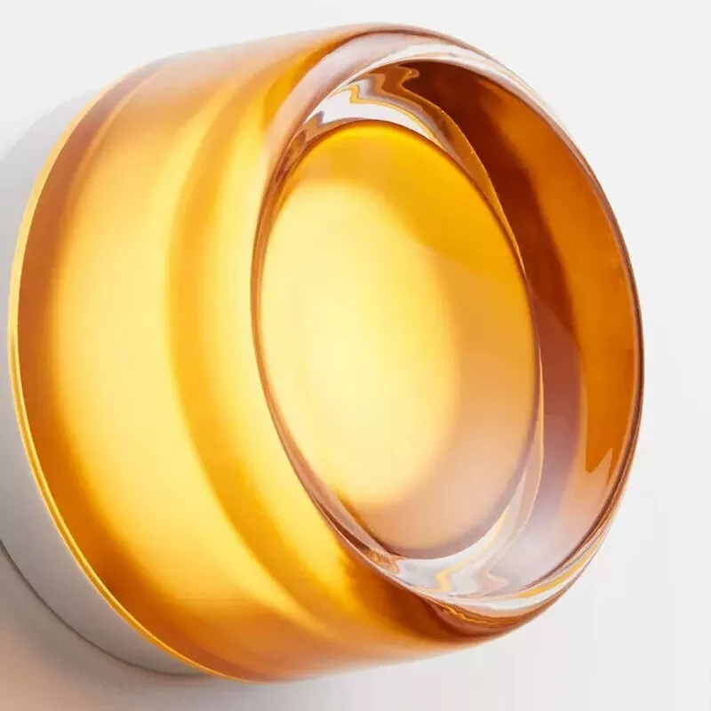 Guldfarvet, rund glaslampe med moderne design på hvid baggrund. Elegant belysning, minimalistisk indretning, skandinavisk stil.