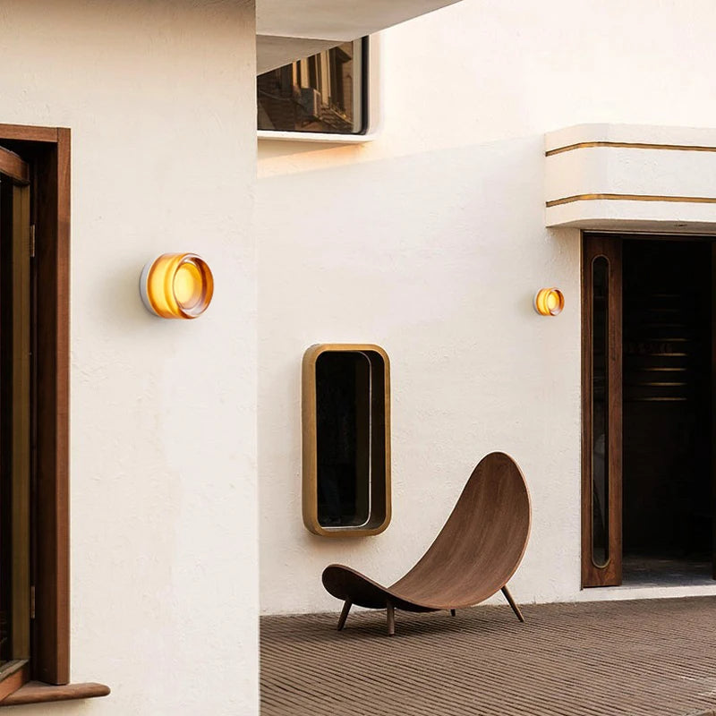 Moderne udendørs gårdhave med stilfuld træstol, væglamper og minimalistisk design. Perfekt til afslapning og moderne boligindretning.