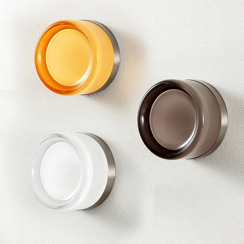 Tre moderne væglamper i forskellige farver: orange, brun og hvid. Minimalistisk design, energibesparende LED-belysning, stilfuld indretning.