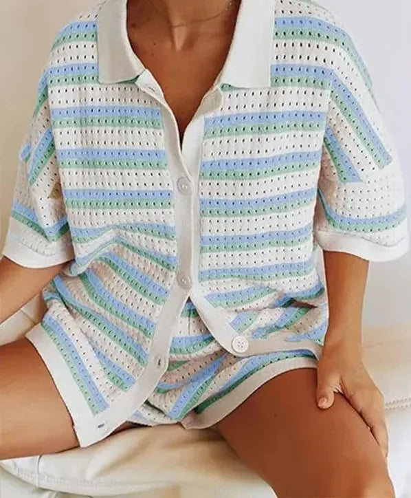 Kvinde iført stribet, hæklet sæt med kortærmet skjorte og shorts i pastelfarver. Sommermode, komfortabelt tøj, trendy design.