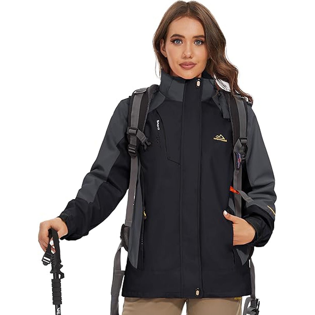 Kvinde iført sort vandtæt jakke med hætte og rygsæk, klar til vandretur. Udendørs beklædning, trekkingudstyr, funktionel jakke til kvinder.