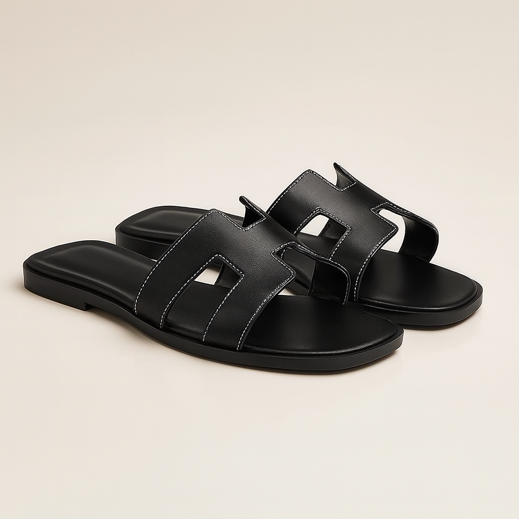 Sort læder sandal med flad sål og åben tå, minimalistisk design, perfekt til sommermode og afslappet stil. Komfortabel og stilfuld fodtøj.