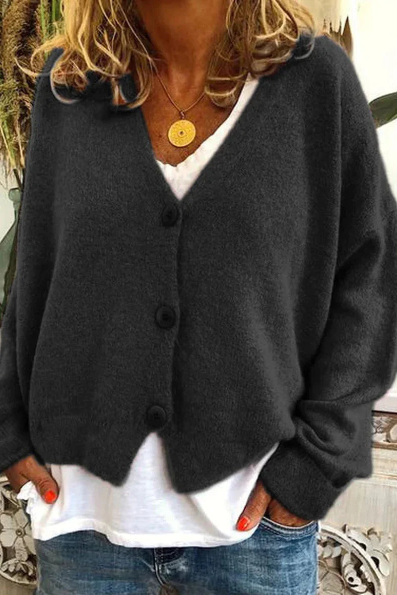 Kvinde iført mørkegrå cardigan med knapper, hvid T-shirt og blå jeans. Casual mode, efterårsoutfit, komfortabelt tøj til kvinder.