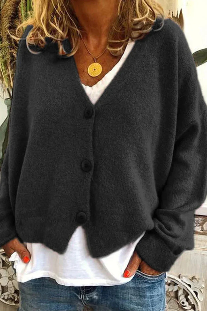 Kvinde iført mørkegrå cardigan med knapper, hvid T-shirt og blå jeans. Casual mode, efterårsoutfit, komfortabelt tøj til kvinder.