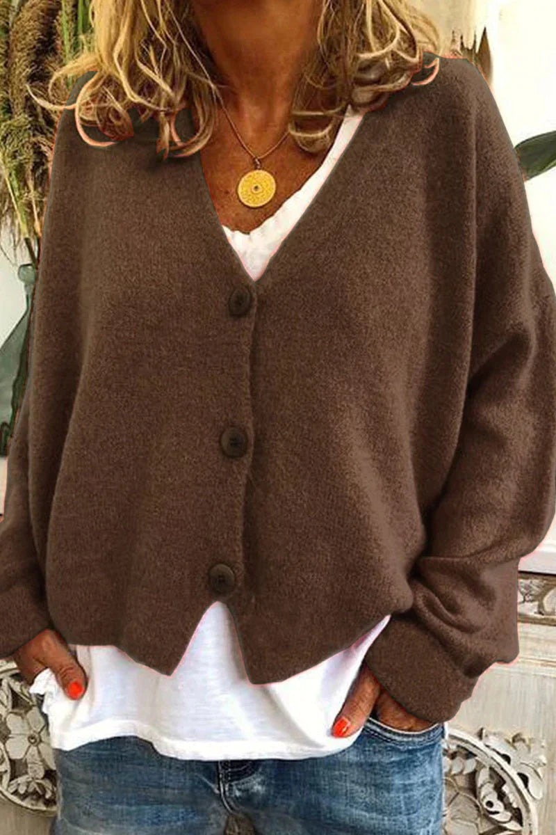 Kvinde iført brun cardigan med knapper, hvid t-shirt og jeans. Afslappet mode, efterårsoutfit, komfortabelt tøj.