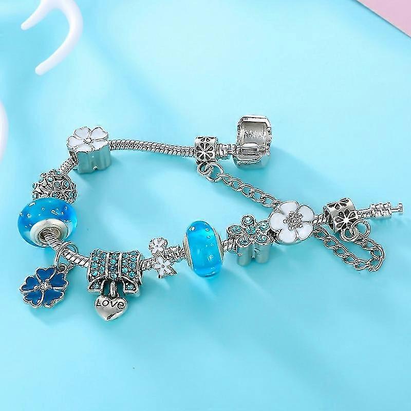 Sølv armbånd med blå og hvide charms, herunder blomster og hjerte med "LOVE". Perfekt tilbehør til kvinder, elegant smykkedesign.