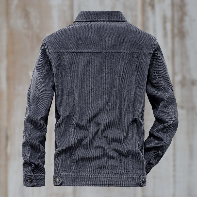 Grå fløjlsjakke set bagfra mod træbaggrund, moderne herremode, stilfuldt design, langærmet, knapdetaljer, casual overtøj.