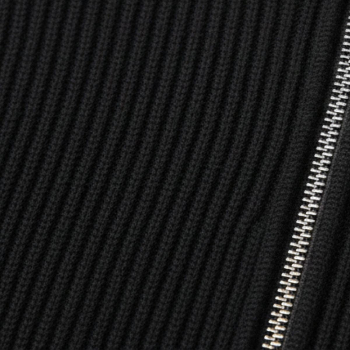 Sort ribstrikket stof med sølv lynlås. Tekstur og lynlåsdetalje fremhæver moderne design. Perfekt til mode- og tekstilbeskrivelser.