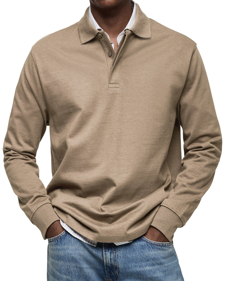 Mand iført beige langærmet polo shirt og blå jeans. Stilfuldt herretøj, afslappet look, moderne mode. Perfekt til hverdagsbrug og casual lejligheder.