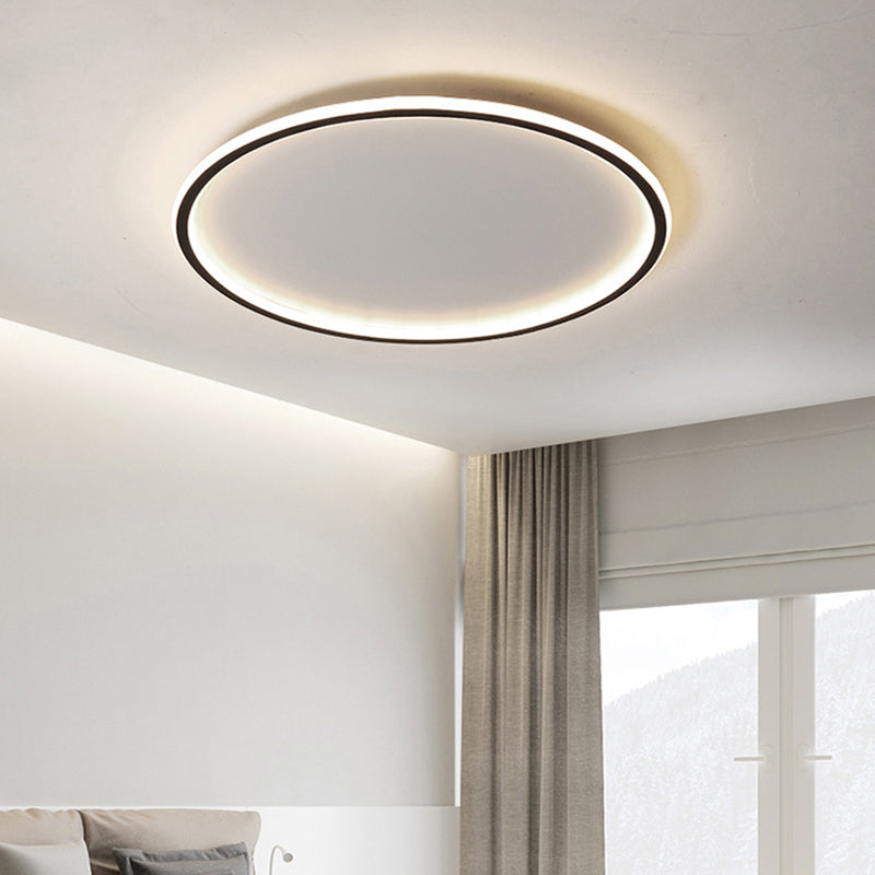 Moderne rund LED-loftlampe i minimalistisk design, monteret i stue med lysegrå gardiner og hvidt loft. Energibesparende belysning.
