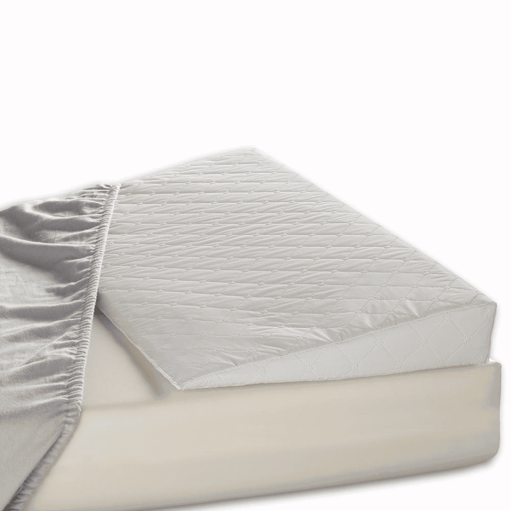 Hvid madras med quiltet topmadras, delvist dækket af gråt sengetøj. Komfortabel og stilfuld sengeløsning til soveværelset.