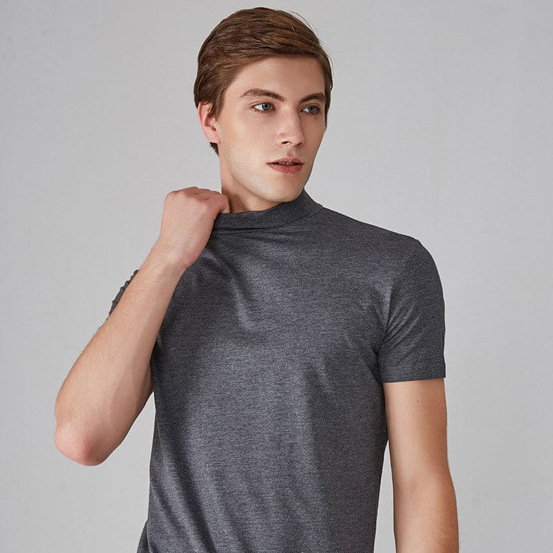 Ung mand iført grå t-shirt, poserer mod neutral baggrund. Moderne herremode, casual stil, kortærmet tøj.