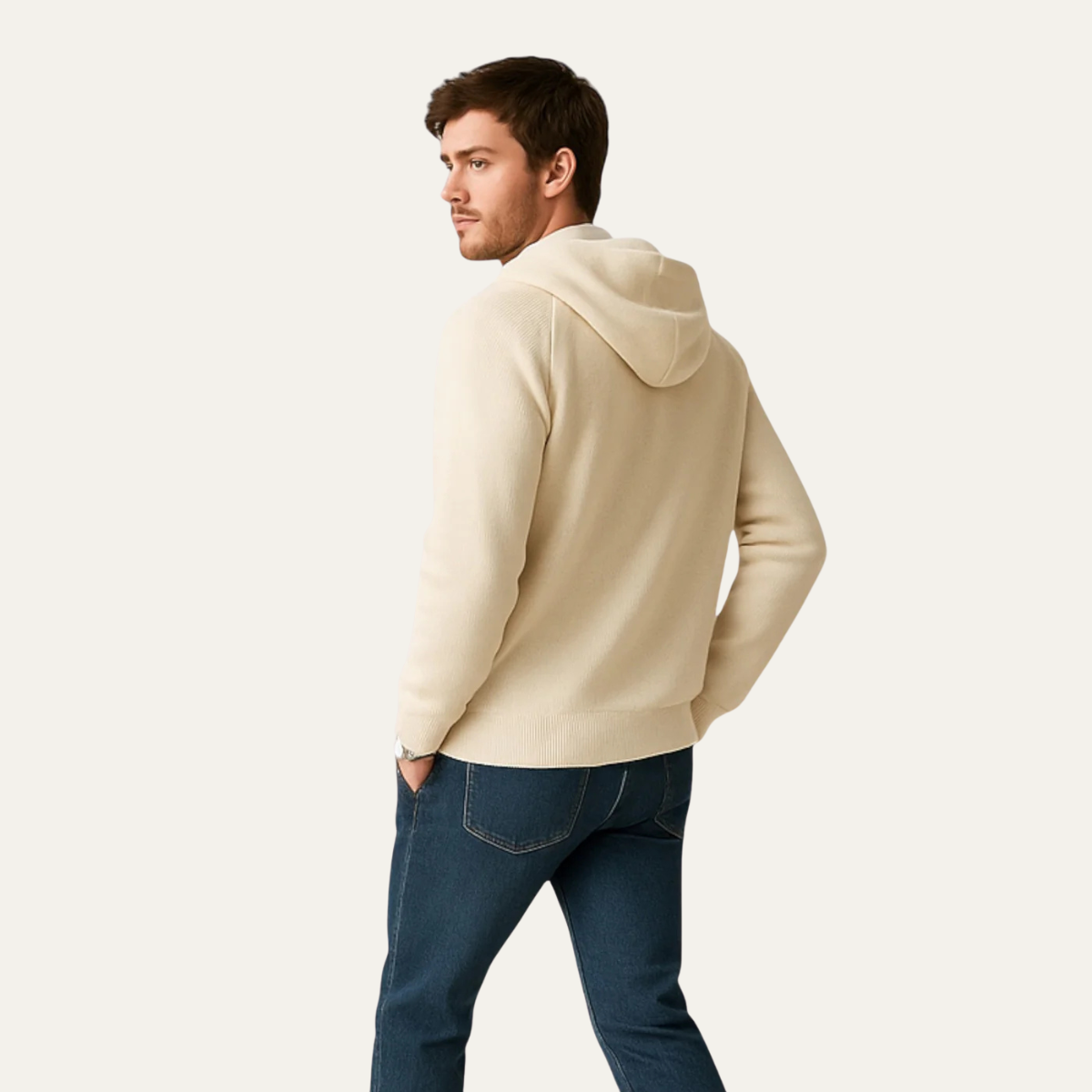 Ung mand iført beige hættetrøje og blå jeans, set bagfra. Moderne herremode, afslappet stil, komfortabelt tøj.