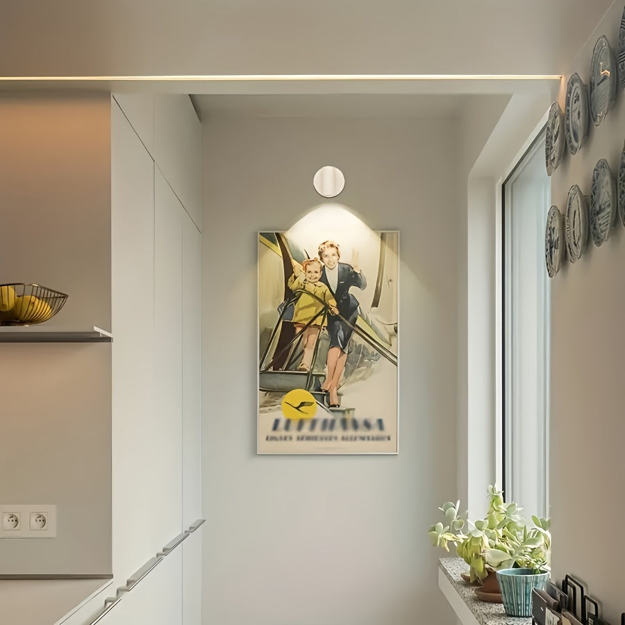 Lufthansa vintage plakat i moderne køkken, vægdekoration med flymotiv, lysegrå vægge, dekorative tallerkener, grønne planter ved vindue.