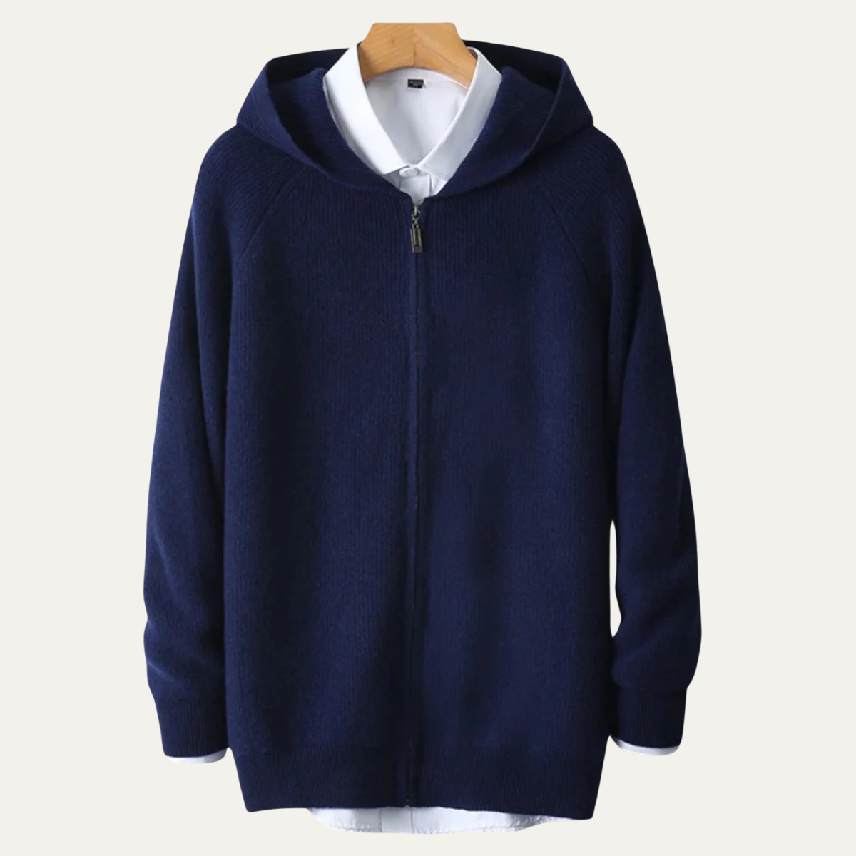 Mørkeblå hættetrøje med lynlås, hængende på bøjle over hvid skjorte. Stilfuld og komfortabel hoodie til mænd, perfekt til casual brug.