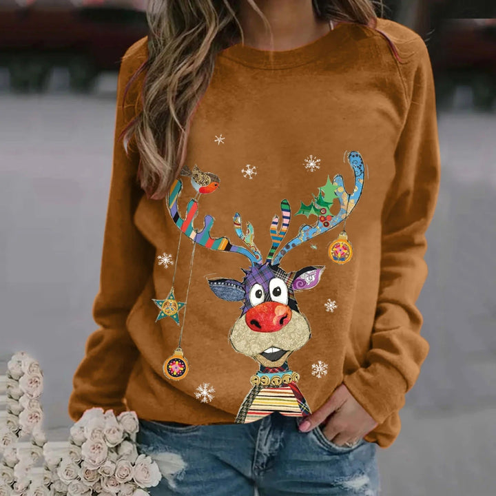 Kvinde iført brun sweatshirt med farverigt rensdyrmotiv, snefnug og julepynt. Perfekt til julemode og vintertøj. Casual og festlig stil.