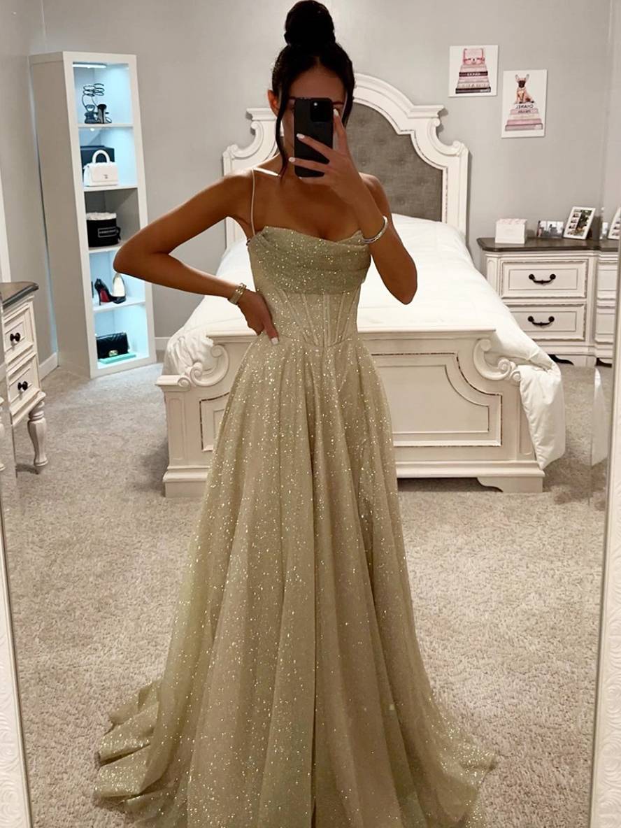 Kvinde i spejl iført glitrende aftenkjole i soveværelse, elegant design, moderne indretning, hvid seng, stilfuld mode, glamourøst look.