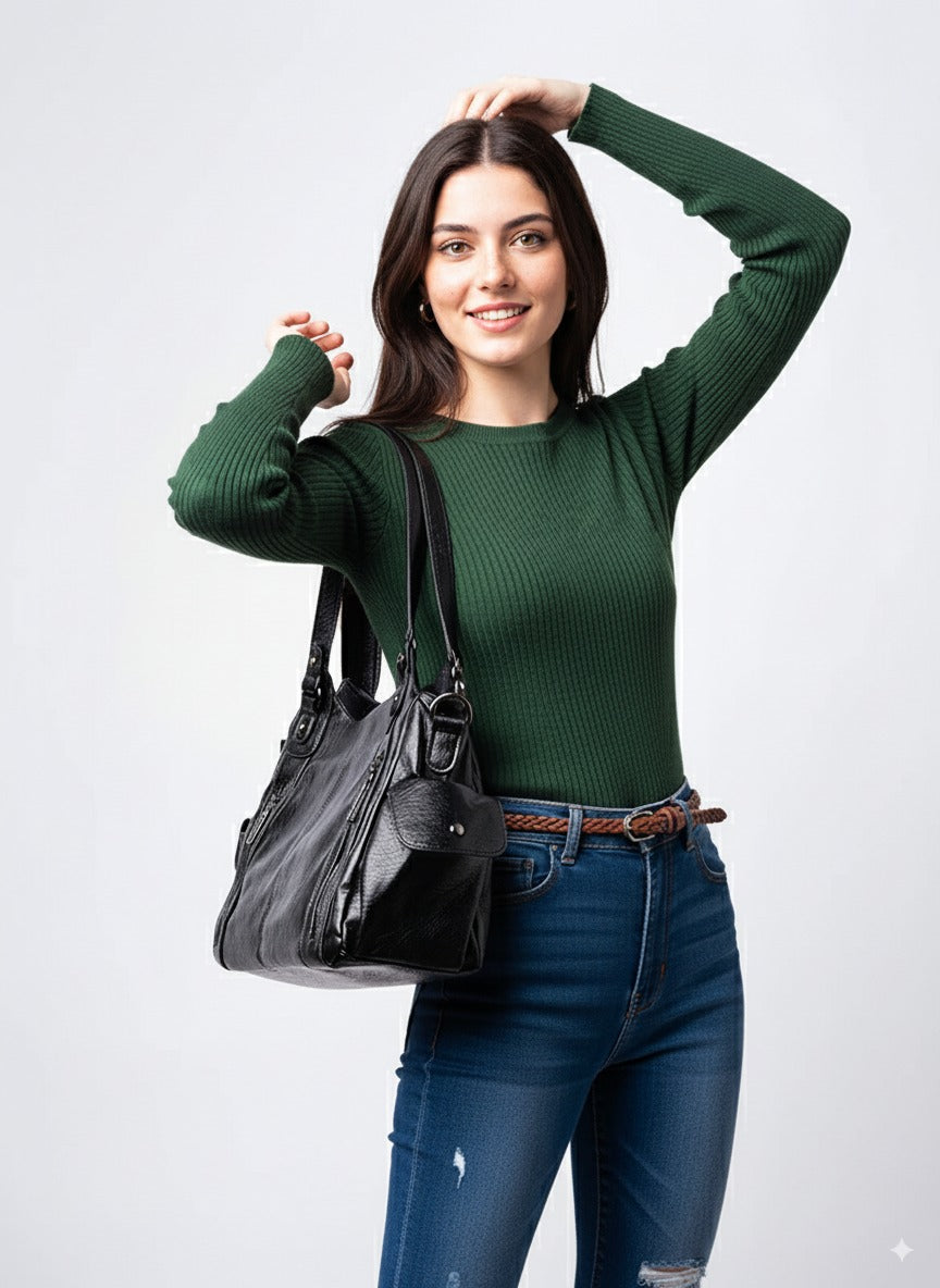 Kvinde i grøn trøje med sort lædertaske, poserer smilende. Mode, stilfuldt tilbehør, casual outfit, jeans. Perfekt til hverdagsbrug.