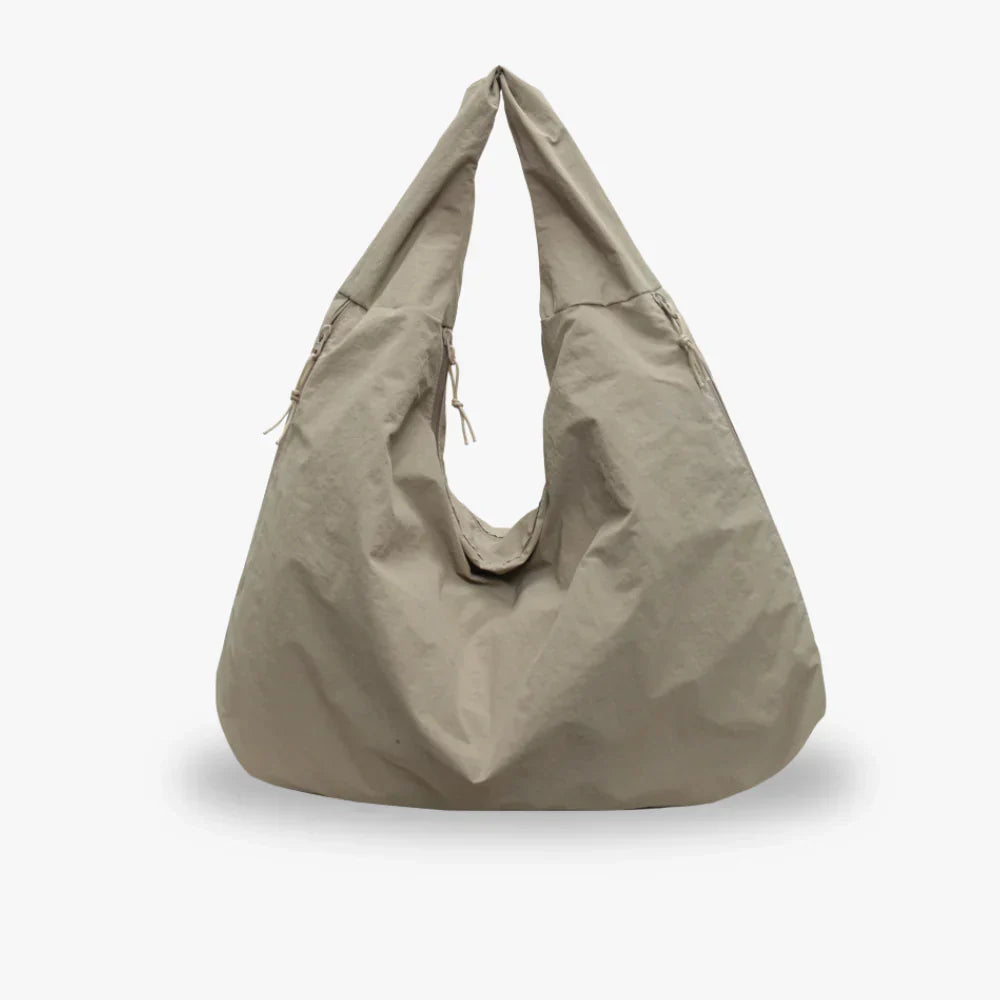 Beige hobo-taske i minimalistisk design, lavet af letvægtsmateriale. Perfekt til hverdagsbrug. Stilfuld og rummelig skuldertaske.