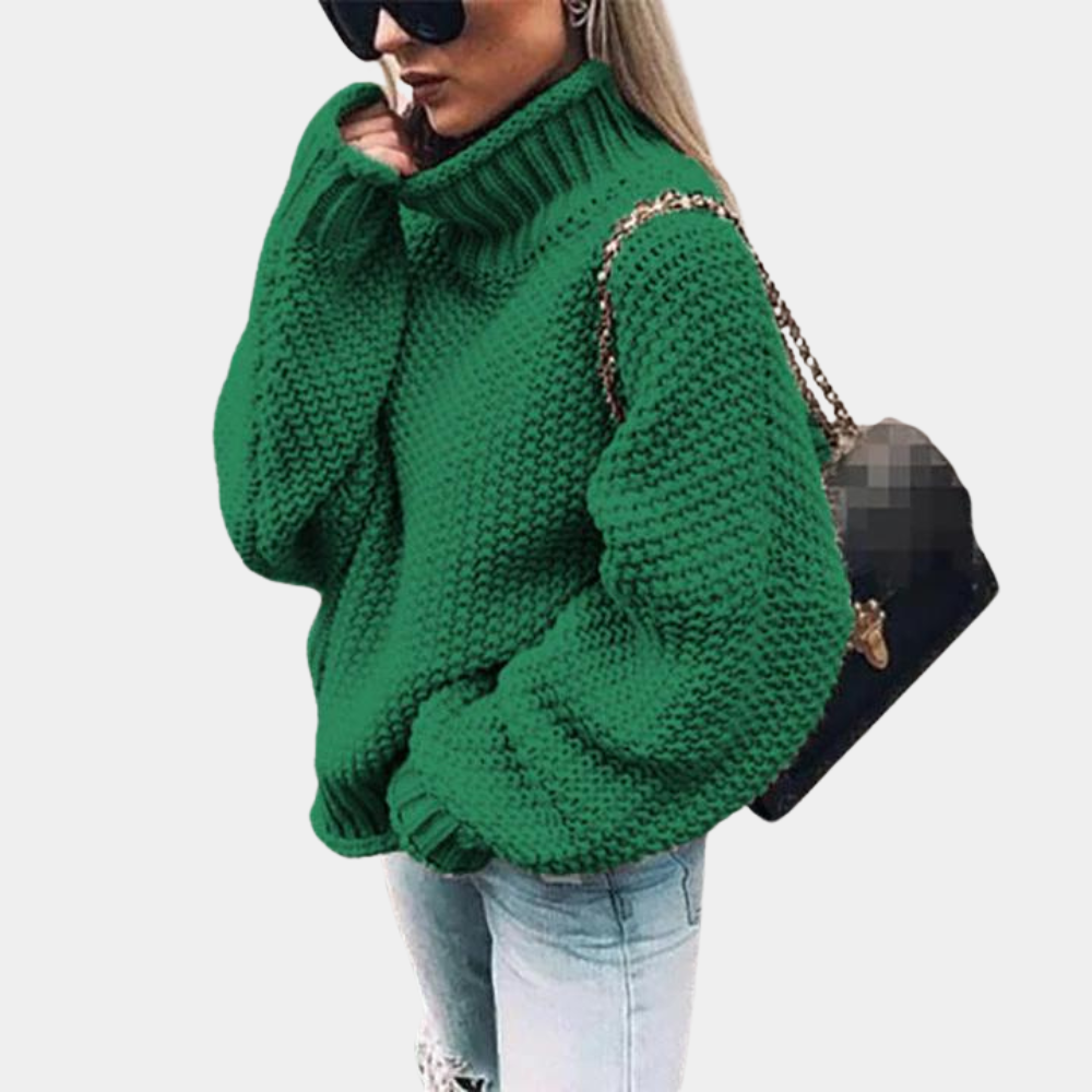 Kvinde iført grøn striktrøje med høj hals, solbriller og sort taske. Trendy vintermode, afslappet stil, varm sweater, moderne accessories.