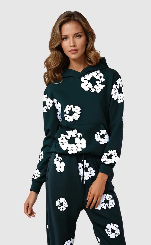 Kvinde iført sort hættetrøje og bukser med hvide blomsterprint, moderne streetwear, afslappet stil, trendy mode, komfortabelt tøj.
