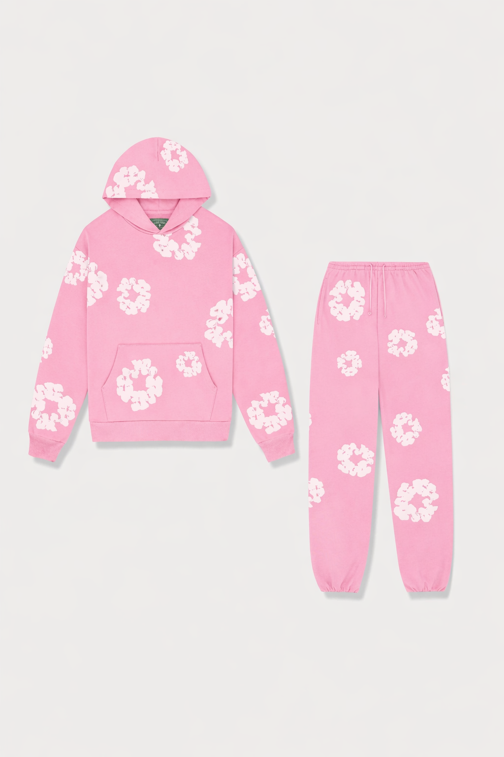 Lyserødt joggingsæt med hættetrøje og bukser, dekoreret med hvide blomsterprint. Komfortabelt og stilfuldt tøj til afslapning og fritid.