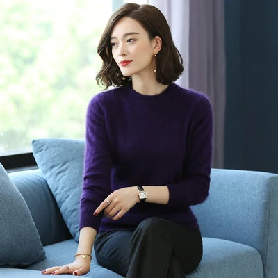 Kvinde i lilla sweater sidder på blå sofa, ser til siden. Moderne indretning, naturligt lys. Stilfuldt look, afslappet atmosfære.