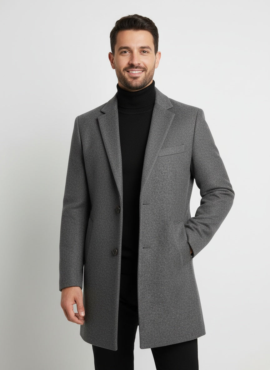 Grå herrefrakke i uld, klassisk design, bæres af mand i sort rullekrave. Stilfuld vintermode, elegant og tidløs beklædning.