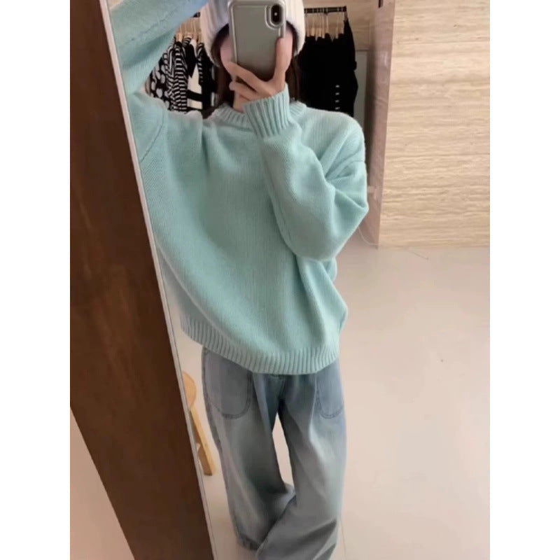 Person iført lyseblå sweater og lyse jeans tager selfie i spejl. Moderne afslappet tøjstil, perfekt til hverdagsbrug.