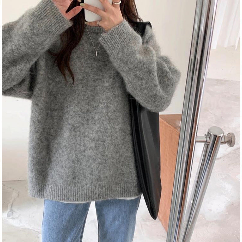 Kvinde i grå striktrøje og blå jeans tager selfie i spejl. Hun bærer en sort taske. Moderne vintermode, afslappet stil, trendy outfit.