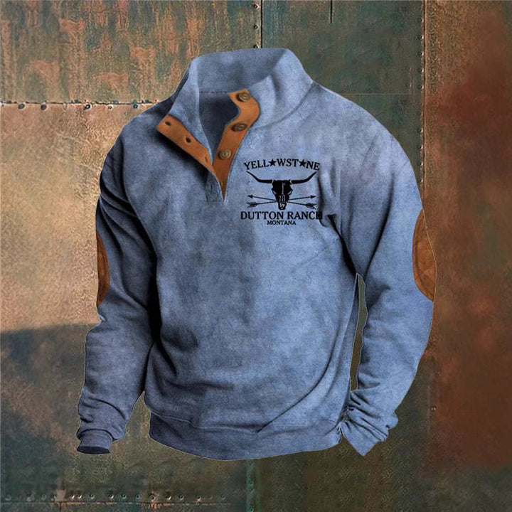Grå sweatshirt med Yellowstone Dutton Ranch-logo, Montana. Designet har brune albuelapper og knapdetaljer. Populær mode, casual stil.