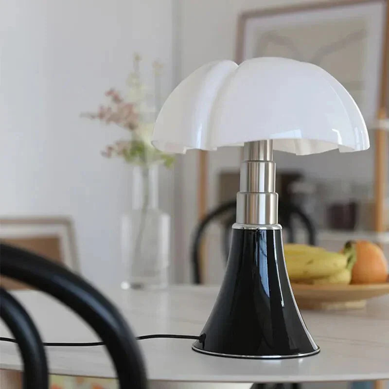 Sort og hvid bordlampe med moderne design på et bord i stue. Baggrund med frugtskål og vase. Stilfuld belysning, indretning, skandinavisk design.