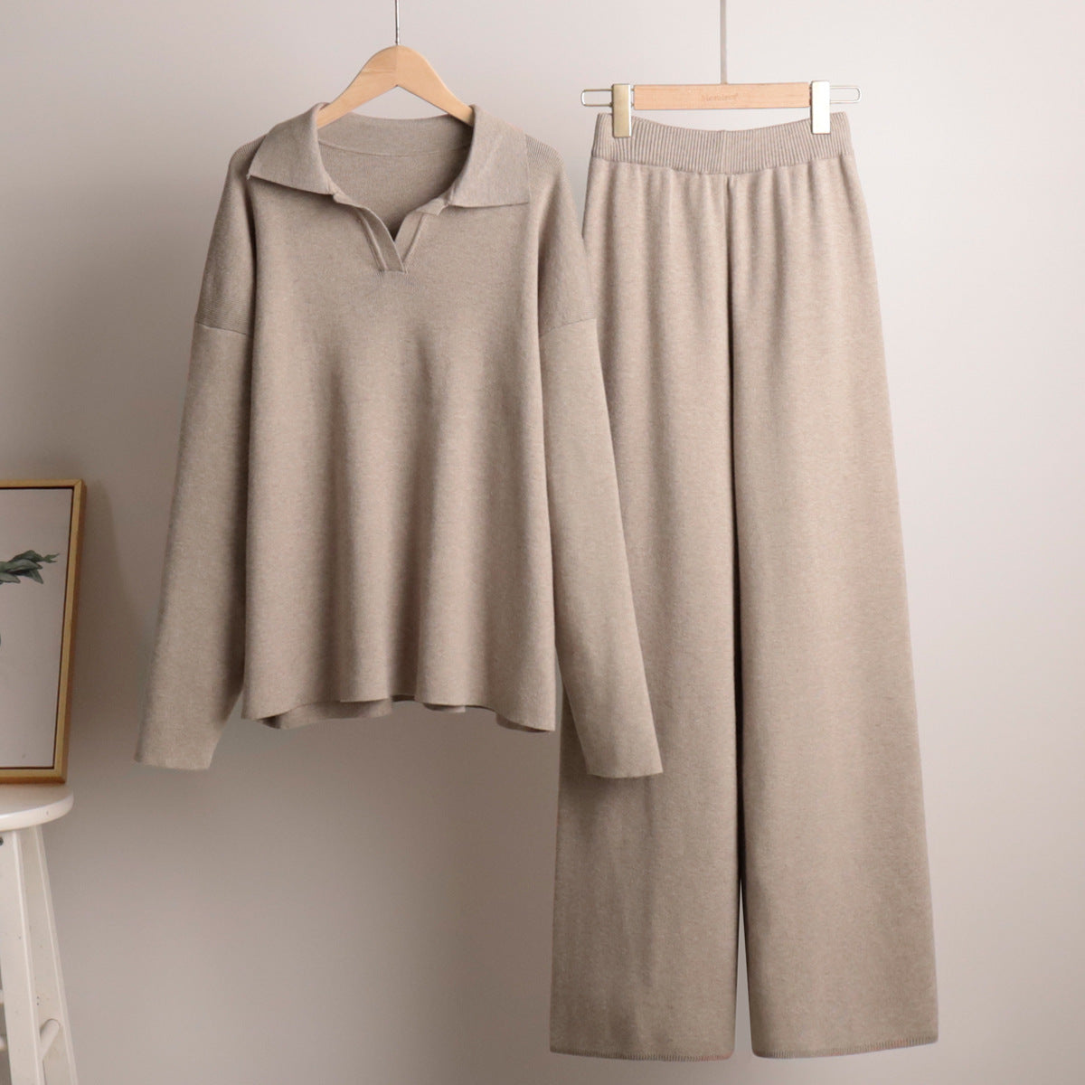 Beige loungewear sæt med langærmet trøje og brede bukser på bøjler. Komfortabelt og stilfuldt tøj til afslapning. Perfekt til hjemmet.