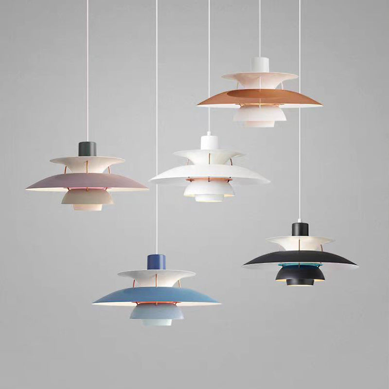 Fem moderne PH-lamper i forskellige farver hænger fra loftet mod en grå baggrund. Designbelysning, skandinavisk stil, indretning.